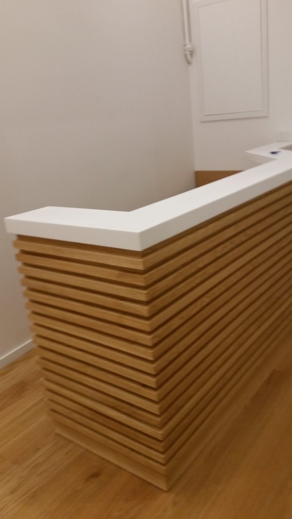 Bancone reception in legno con piano bianco in una stanza moderna