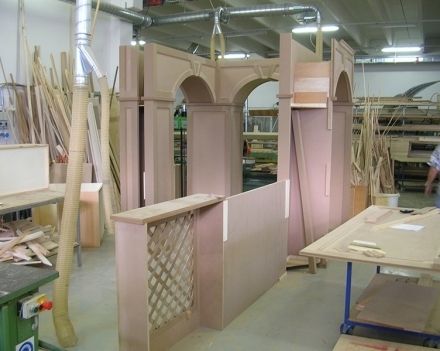 Laboratorio con elementi architettonici rosa e archi in costruzione tra pannelli di legno e attrezzi