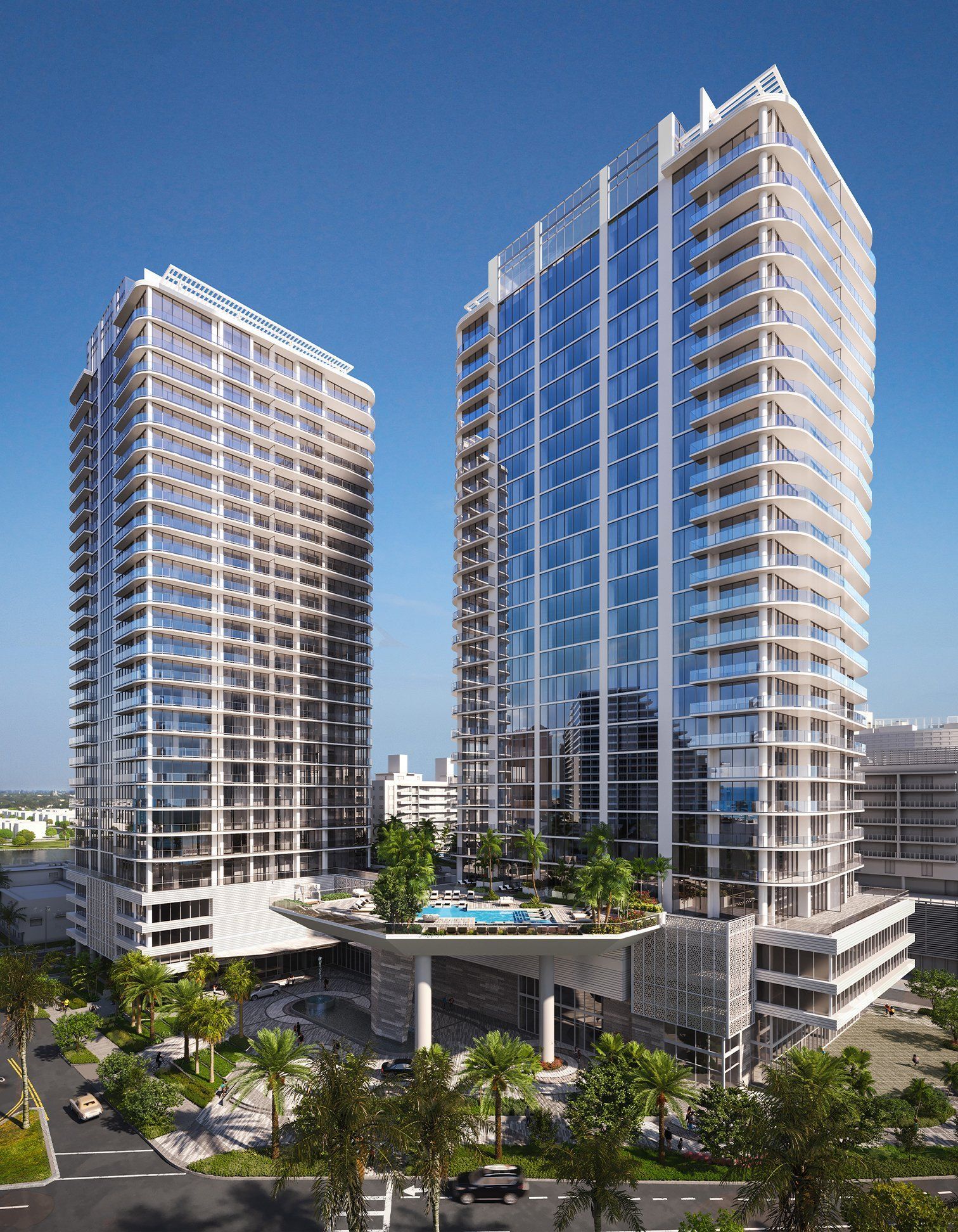 Two modern high-rise apartment towers with a pool deck against a clear blue sky