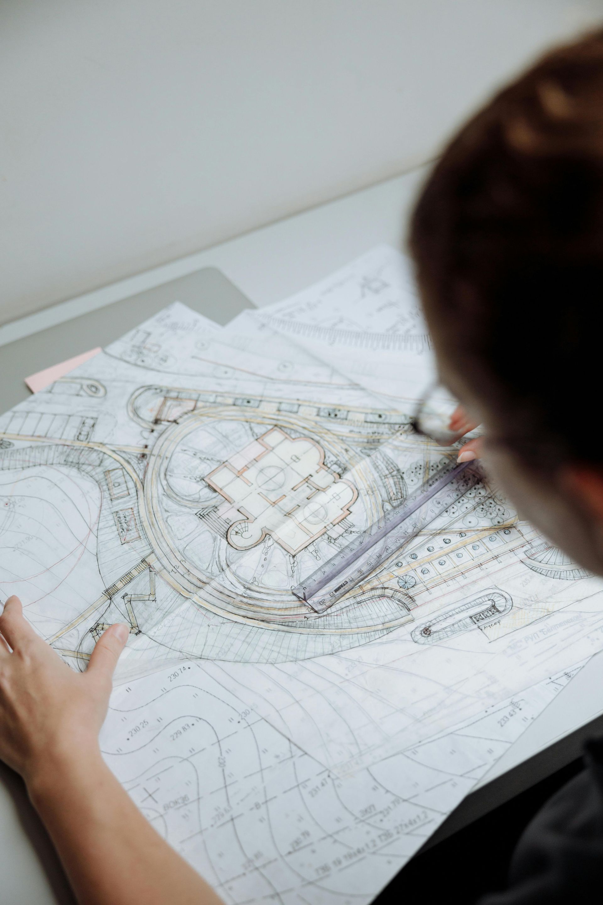 Person sketching a detailed circular architectural plan on white paper with a pencil
