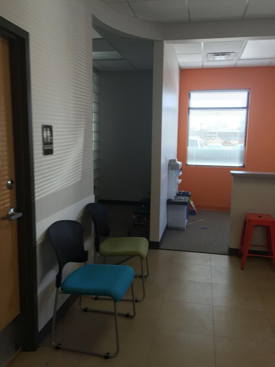 Waiting area with chairs, orange wall, water cooler, and window.