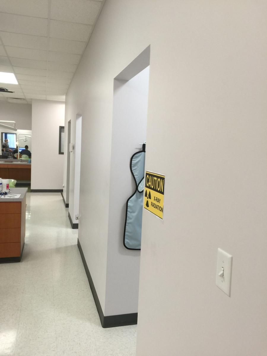 Hallway in a medical office with open doorway and lead apron. 