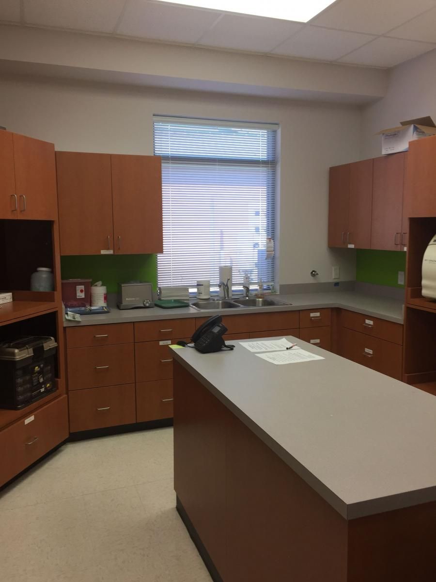Kitchen area with brown cabinets, gray countertops, and a central island. A window with blinds is in the background.