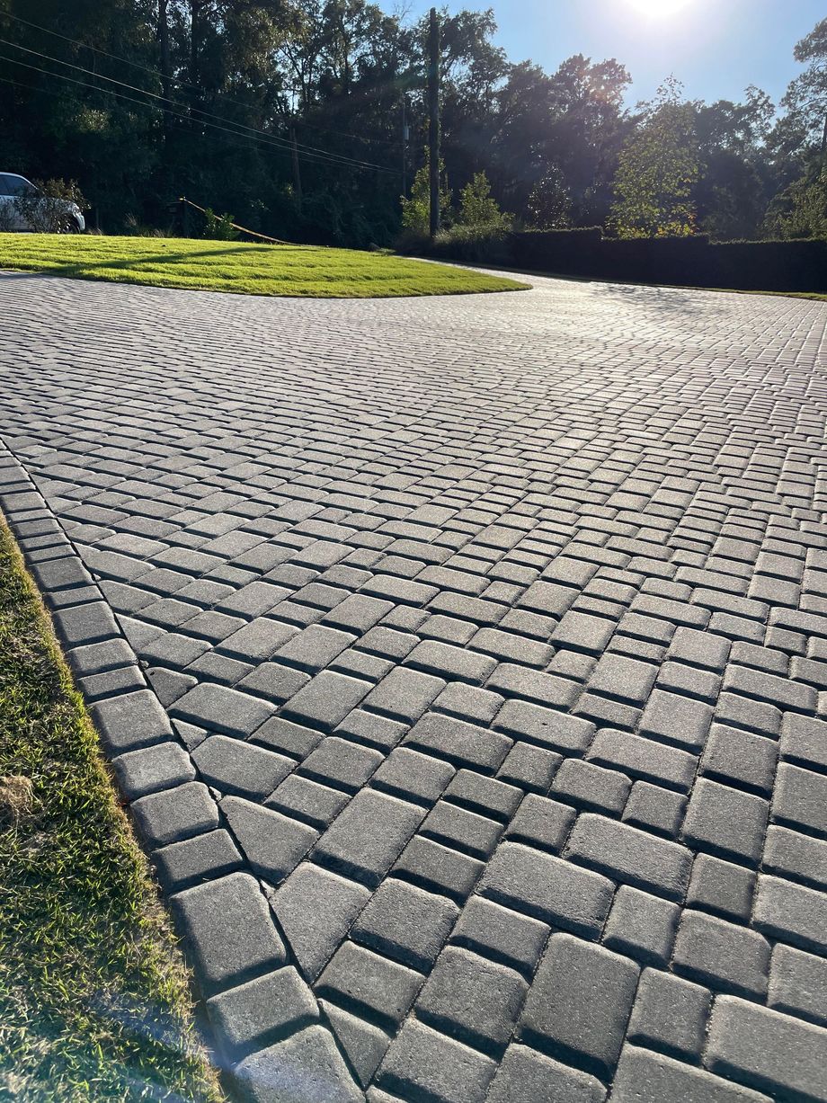 A brick driveway with trees in the background