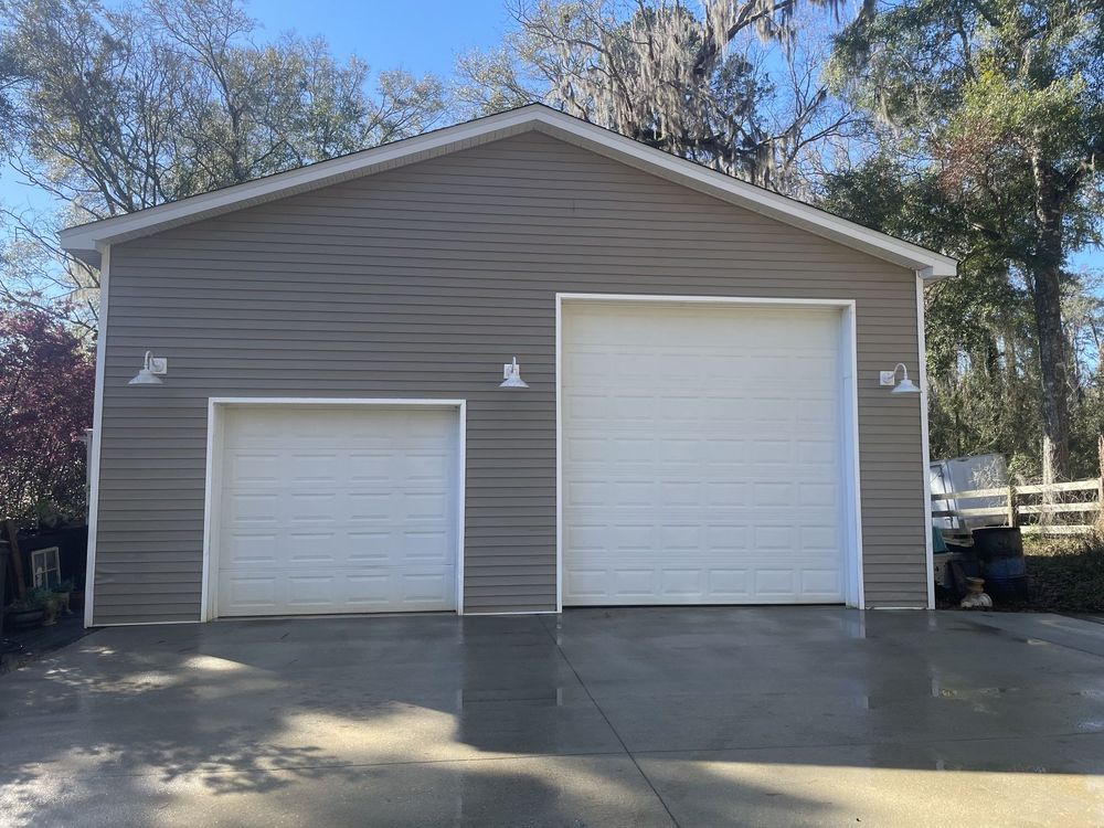 A garage with two garage doors and a driveway in front of it.