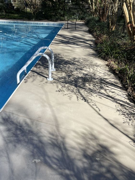 A swimming pool with a concrete walkway leading to it