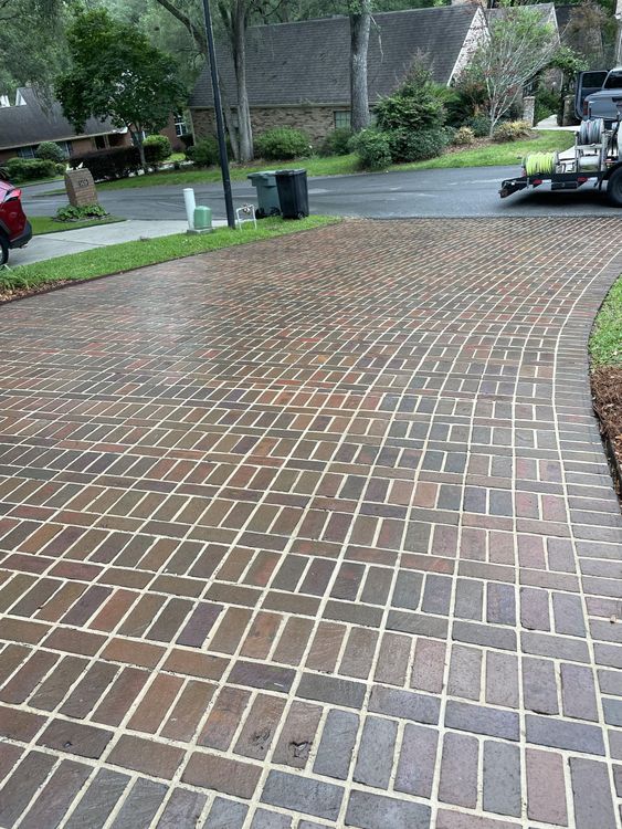 A brick driveway with a car parked on the side of it