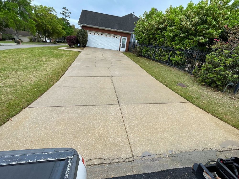 A concrete driveway leading to a house with a white garage door.