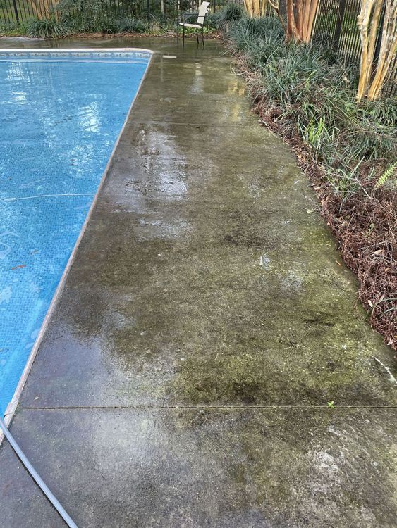 A dirty concrete walkway next to a swimming pool.