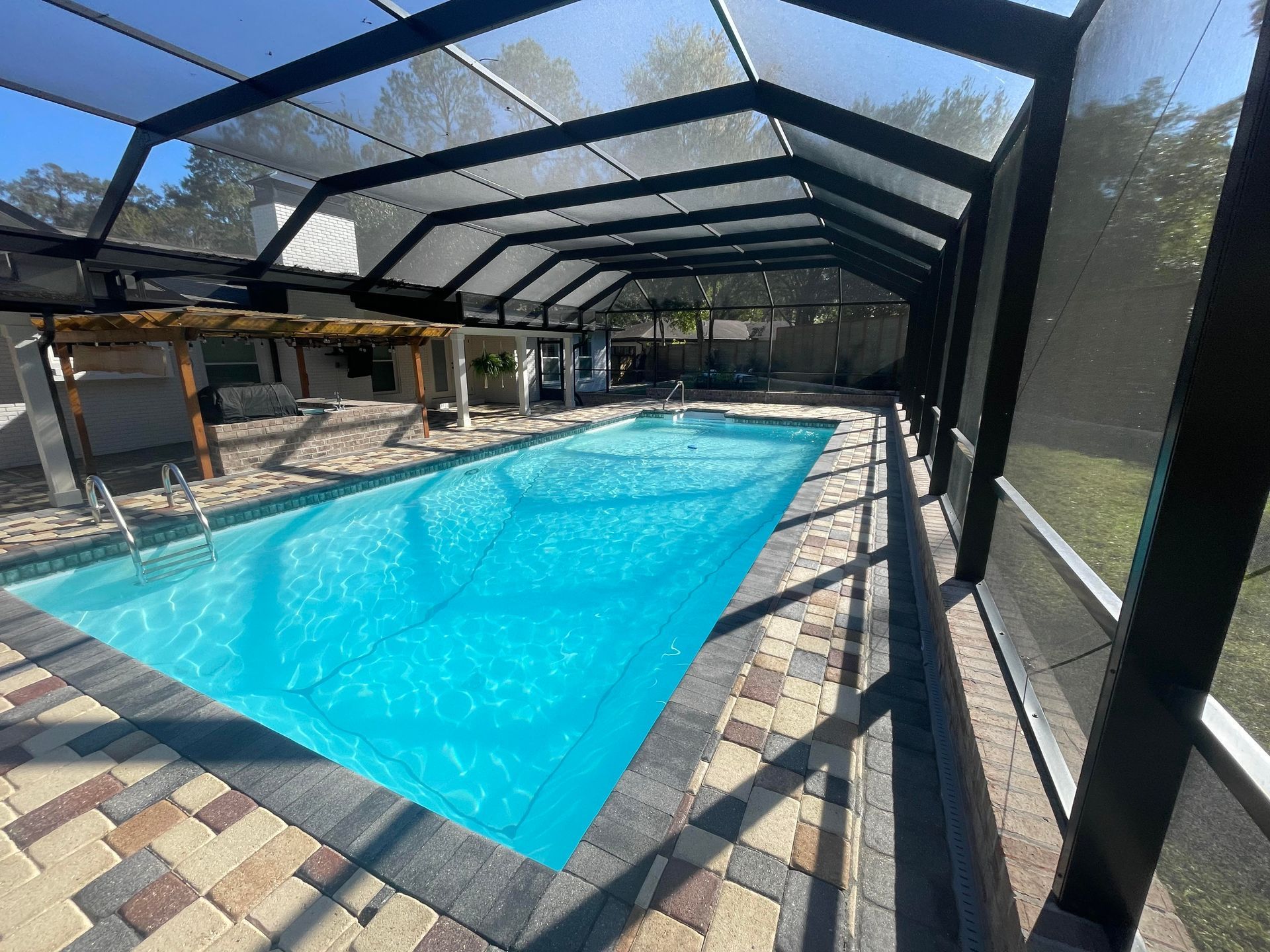 A large swimming pool is under a screened in area.