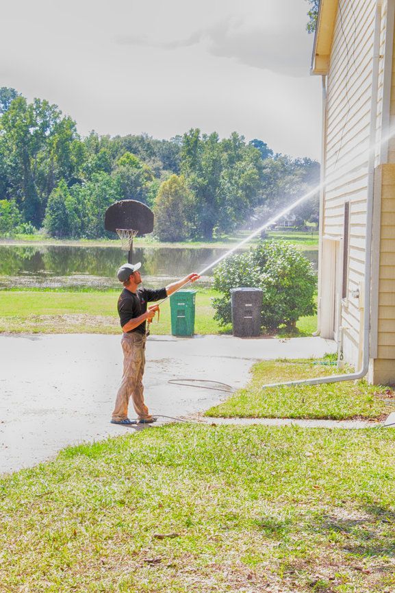 A man is cleaning a sidewalk with a high pressure washer.