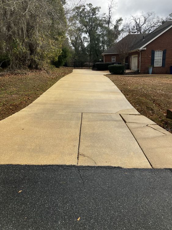 A concrete driveway leading to a brick house