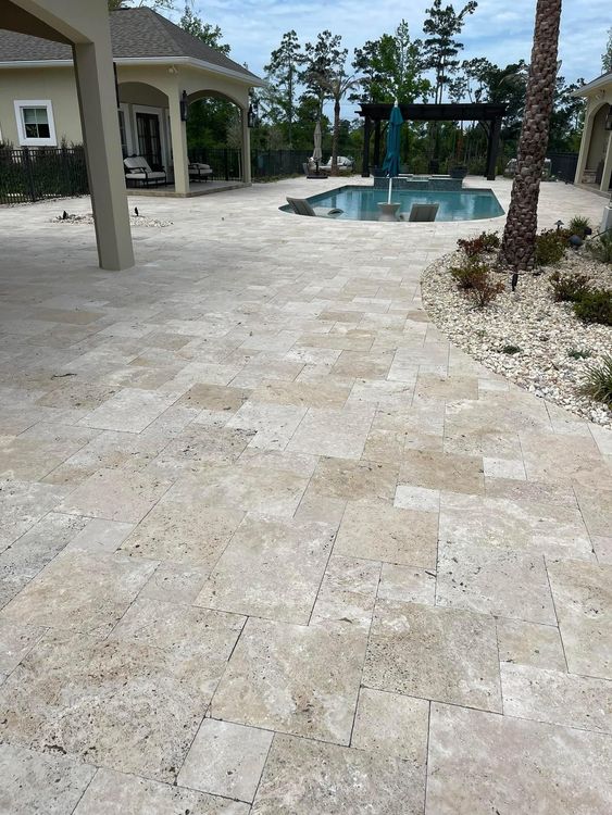 A patio with a pool and a house in the background.