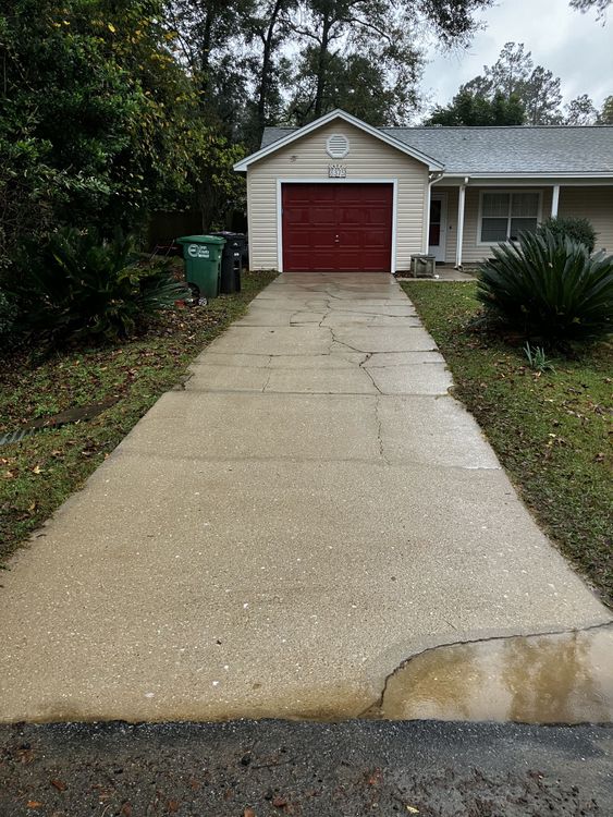 A concrete driveway leading to a house with a red garage door