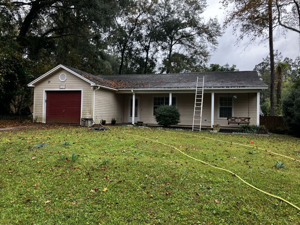 A house with a red garage door and a ladder in front of it.