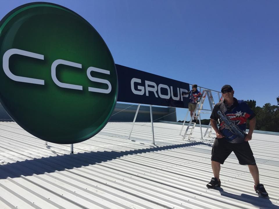 A Man Is Standing On A Roof Next To A Large Sign That Says CCS Group — Capital Signs in Fyshwick, ACT