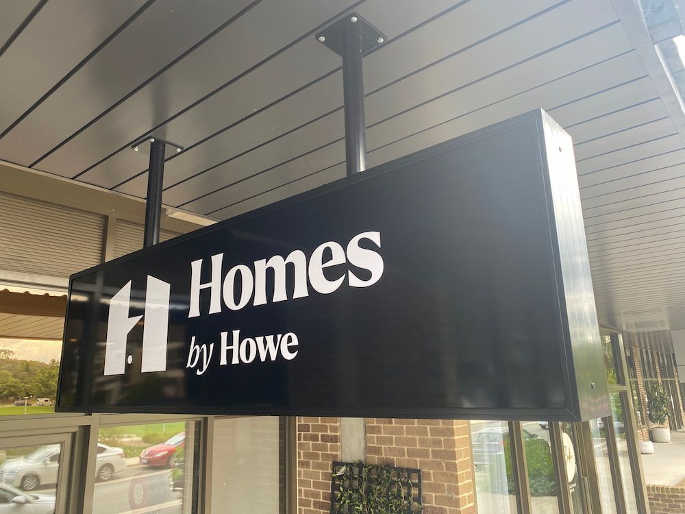 A Sign For Homes By Howe Is Hanging From The Ceiling Of A Building — Capital Signs in Fyshwick, ACT