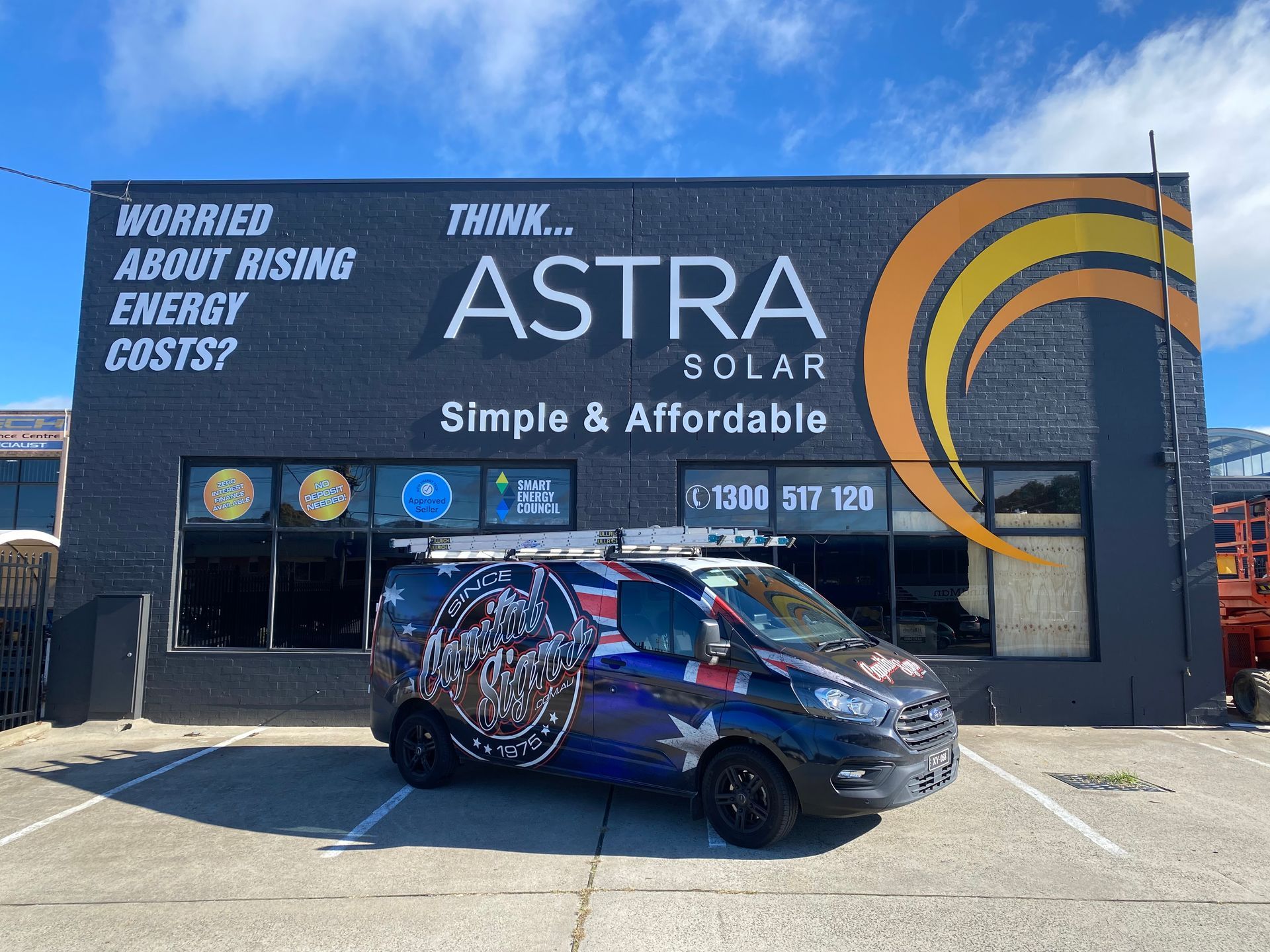 A black Astra Solar building with a solar panel van parked in front under a blue sky. — Capital Signs in Fyshwick, ACT