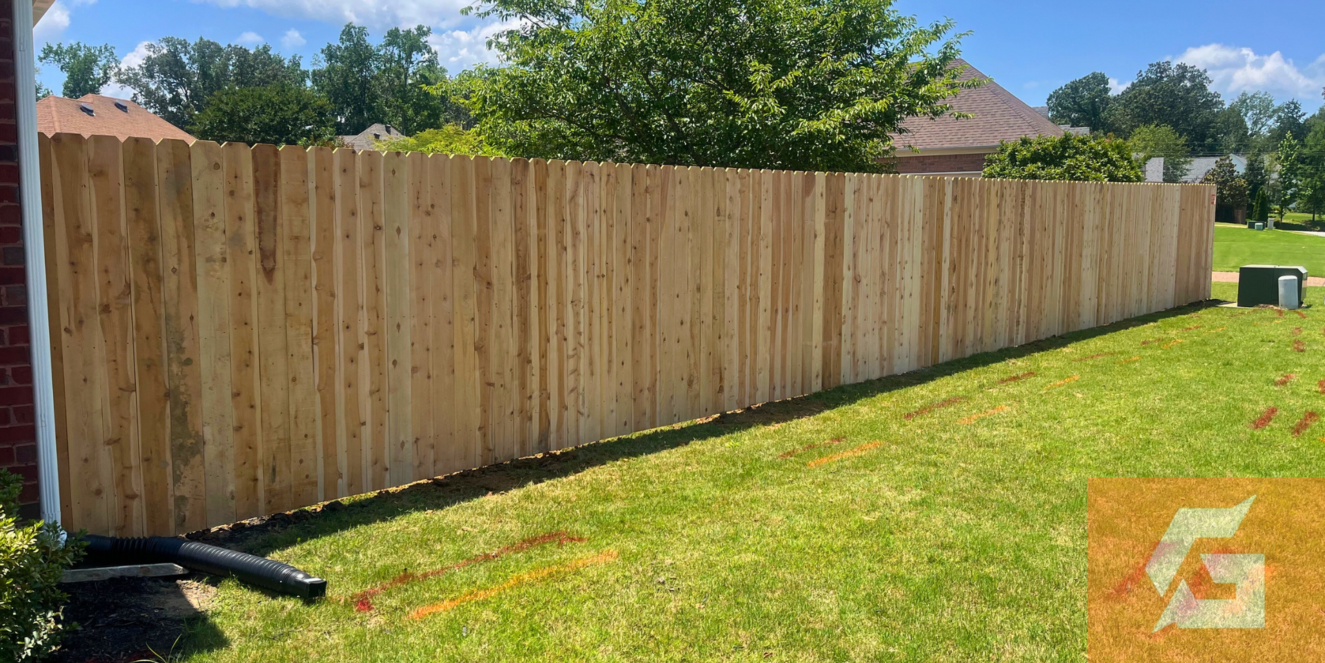 Wooden fence in a grassy yard under a blue sky.