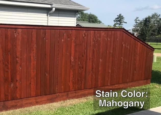 Mahogany-stained wooden fence with a house in the background, set on a grassy lawn.