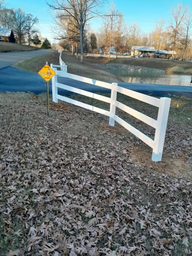 White split-rail fence along a road, with a 
