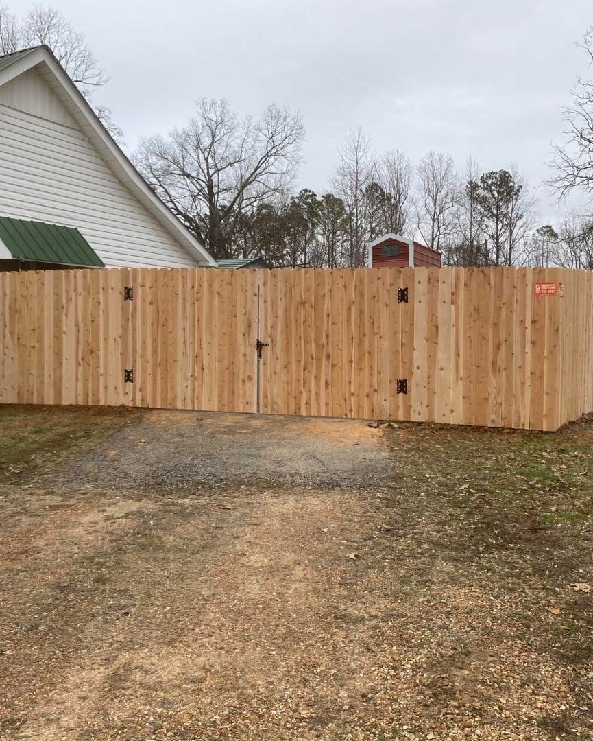 Wooden fence, light brown, in front of a building. Gate in center. Cloudy sky.