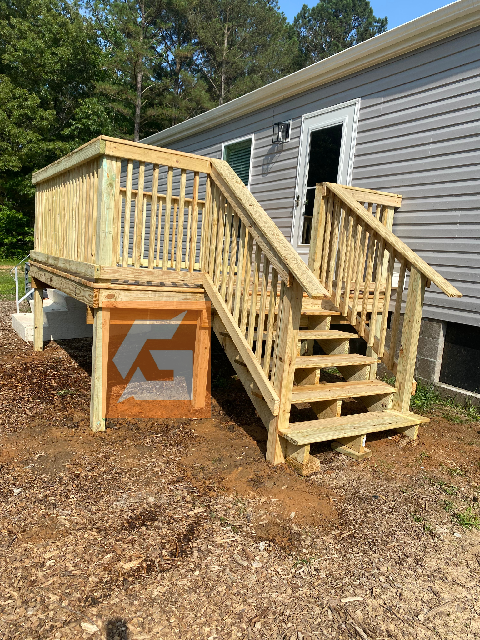 Wooden deck and stairs leading to a doorway on the side of a light grey house.