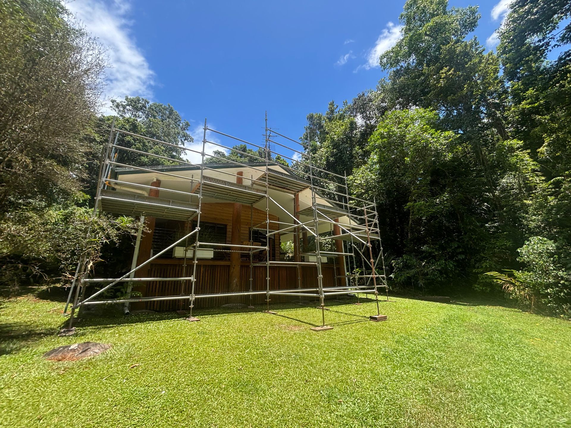 Small house surrounded by scaffolding in a sunny green yard with trees and blue sky — Underdog Edge Protection in Redlynch, QLD