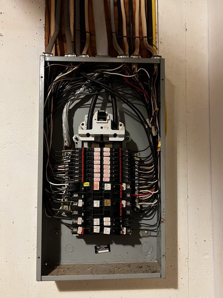Electrical panel with numerous wires and circuit breakers.