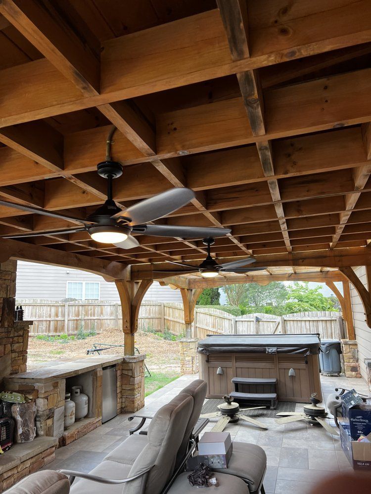 Outdoor patio with wooden pergola, ceiling fans, hot tub, and seating.