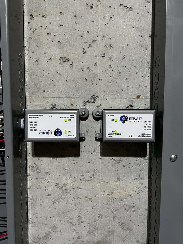 Two electrical boxes mounted on a concrete pillar, each with a display and cabling.