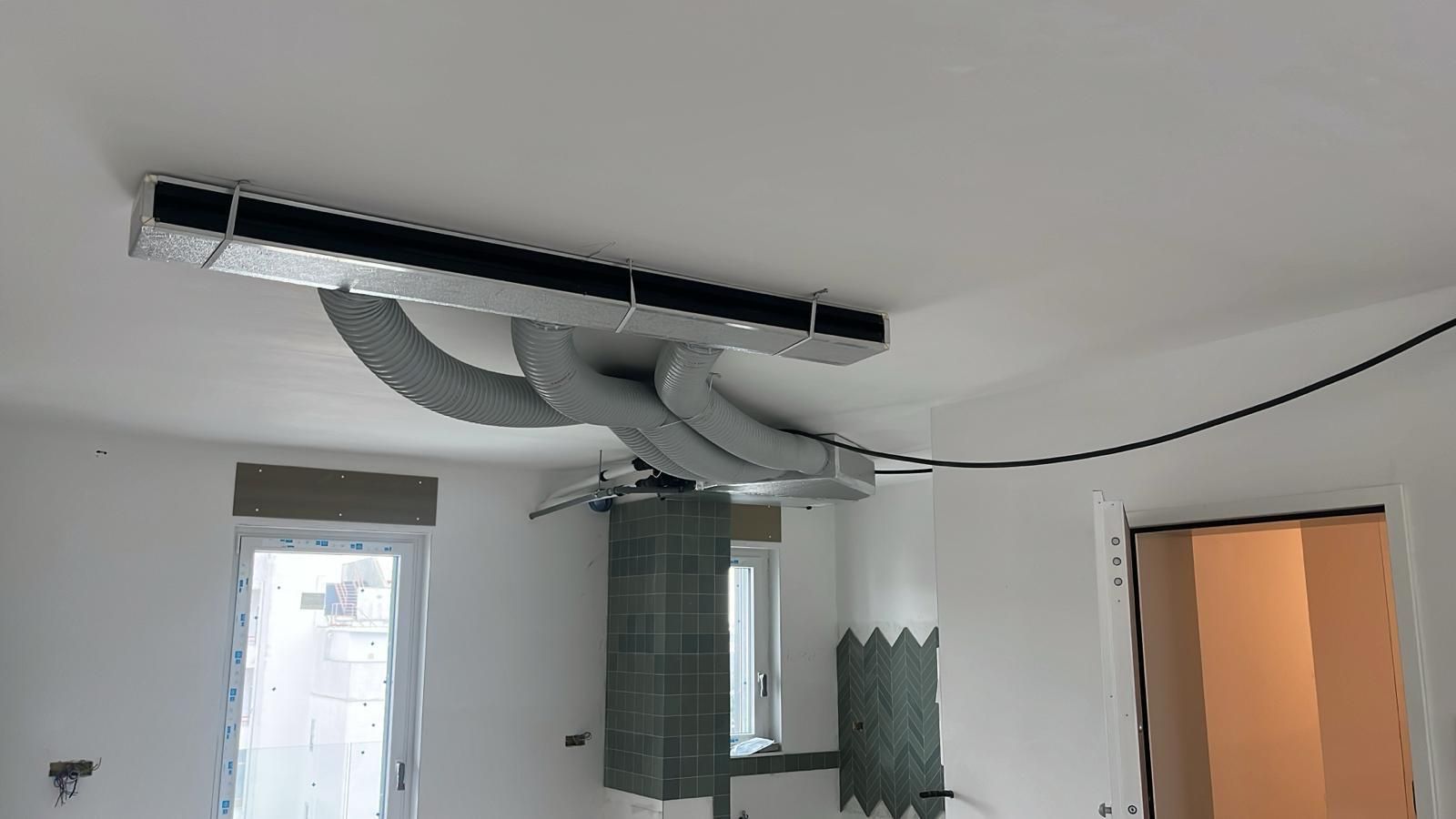 Sistema HVAC installato in una stanza con pareti bianche e condotti collegati a un'unità a soffitto.