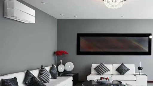 Soggiorno moderno con divani bianchi, pareti grigie e aria condizionata.