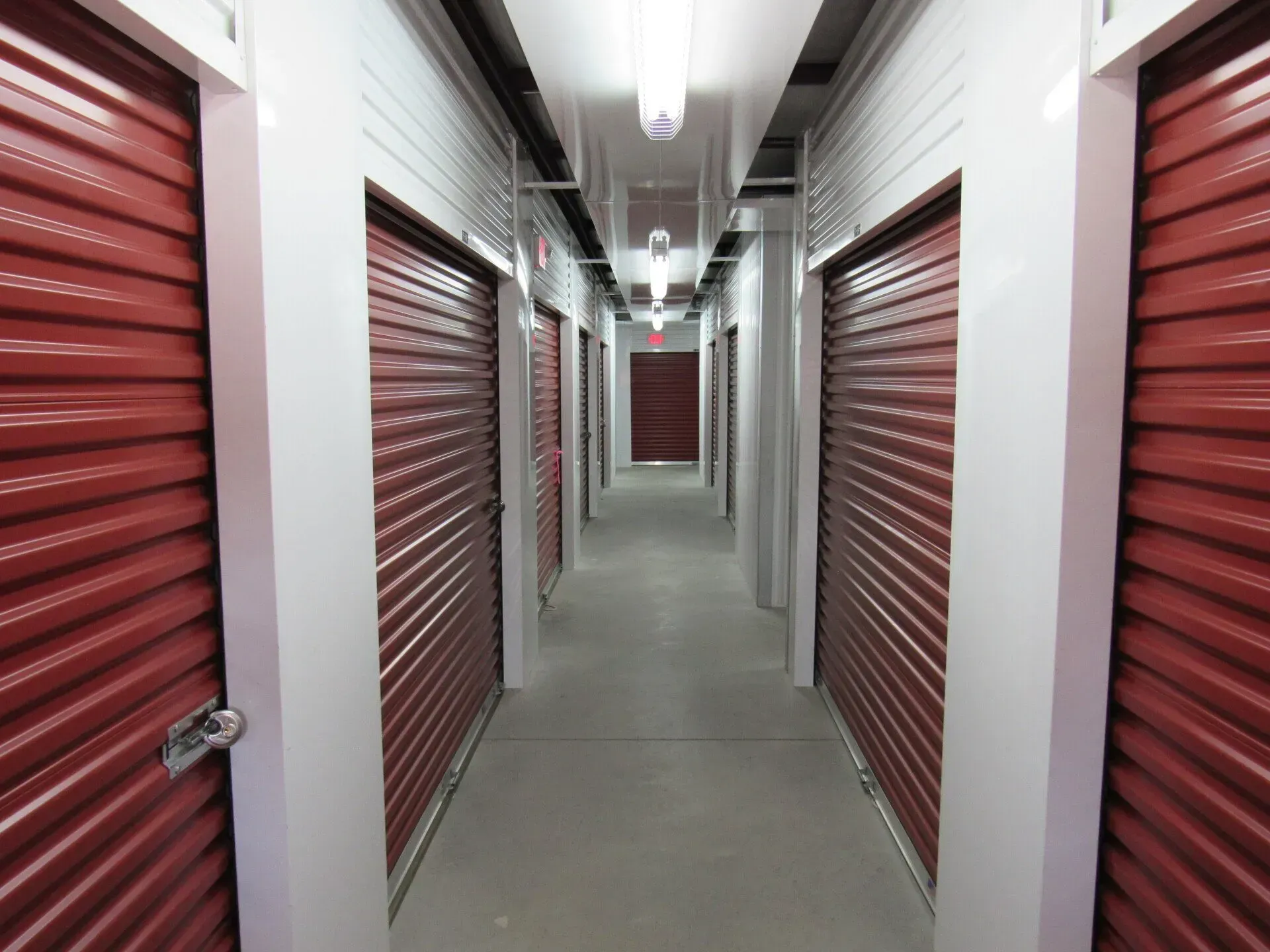 Interior view of storage units, with red doors lining a hallway.