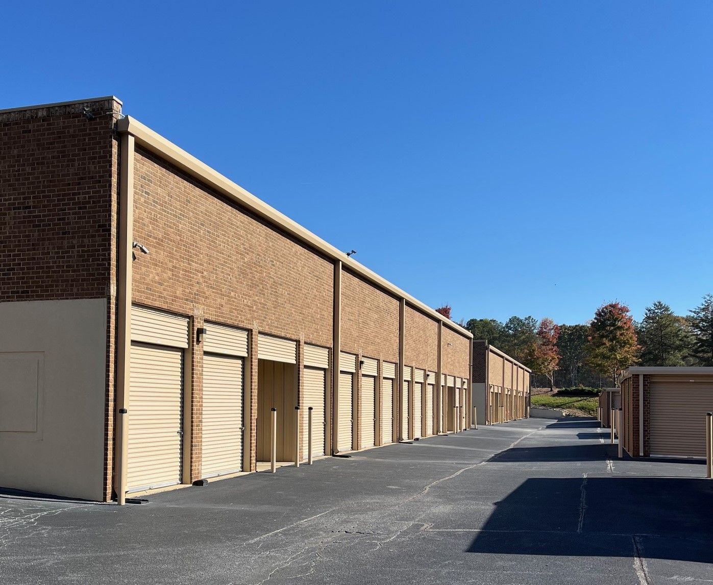 Red storage unit doors along a gravel path under a blue sky with clouds.