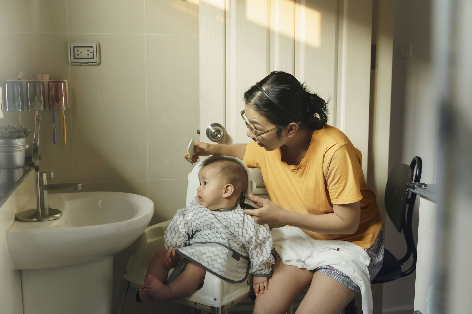 Woman with a baby in a bathroom; woman is showing something to the baby.