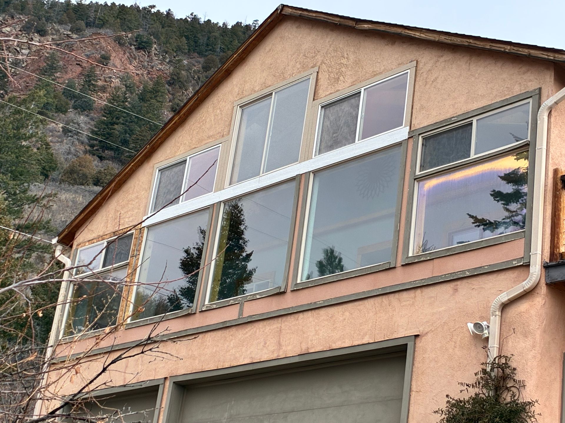 Mountain house with large windows and a peach stucco facade, set against a rocky hillside