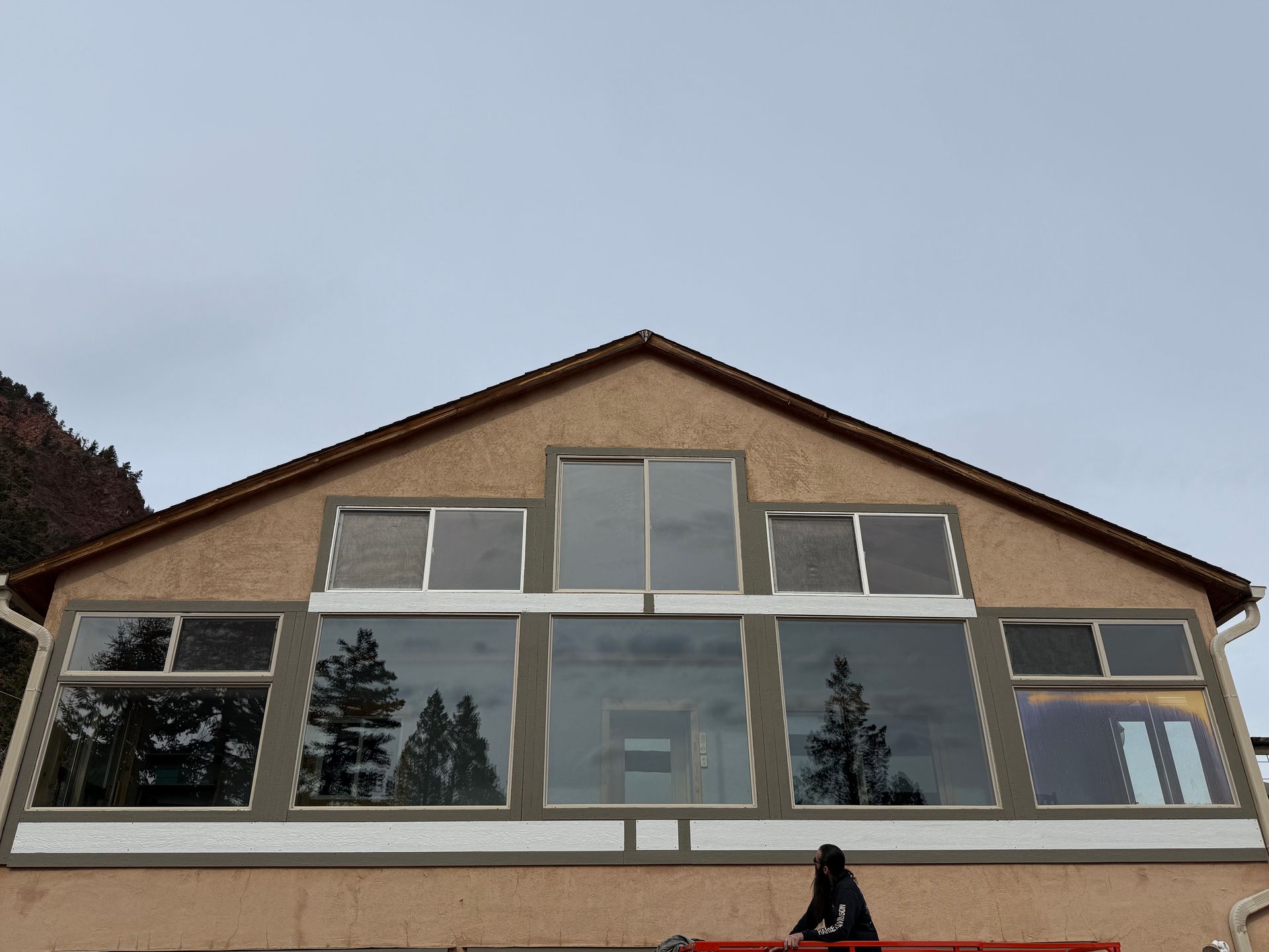Two-story house exterior with large front windows under a gray sky