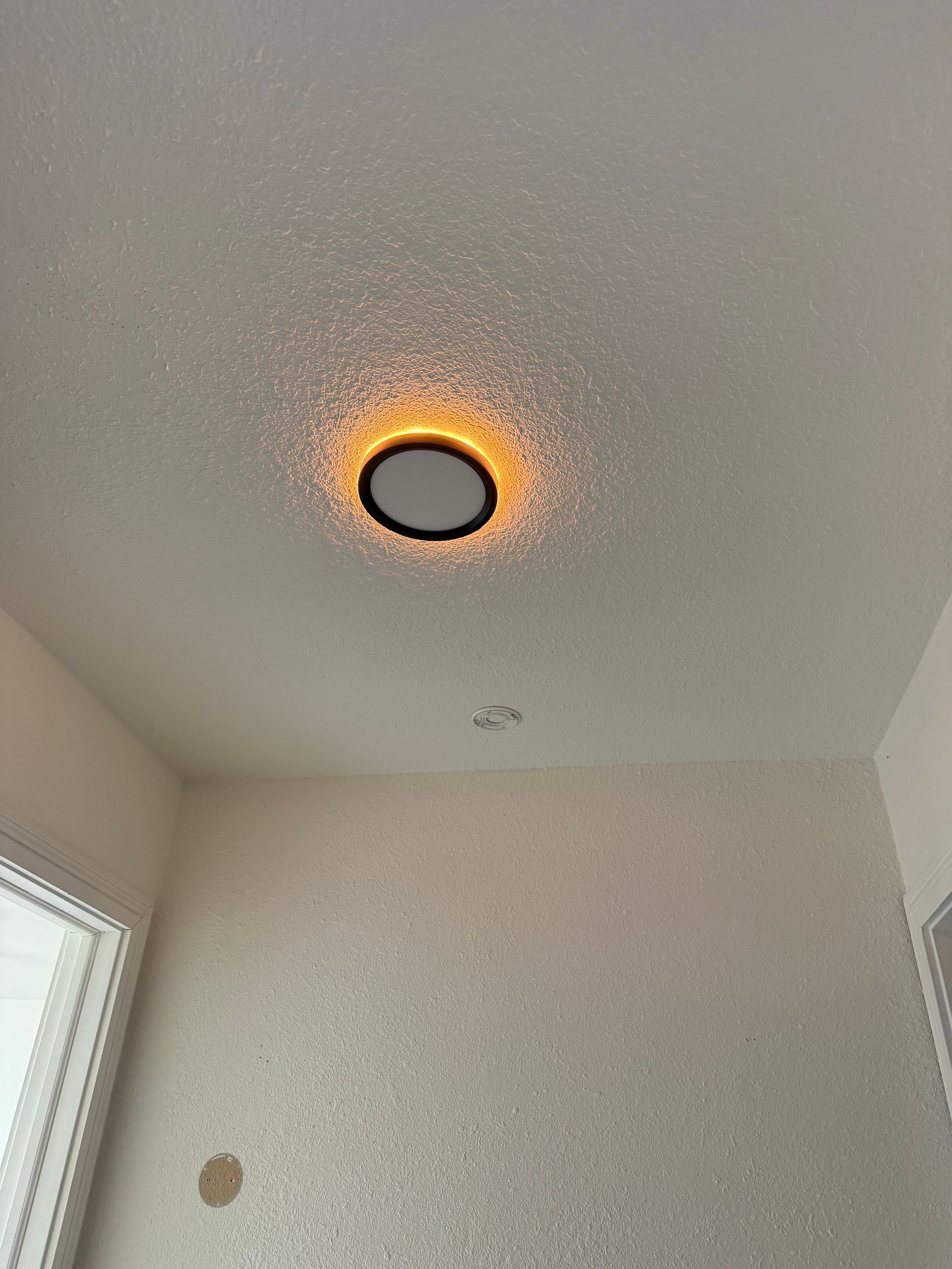 Ceiling light with warm orange glow in a plain white room.