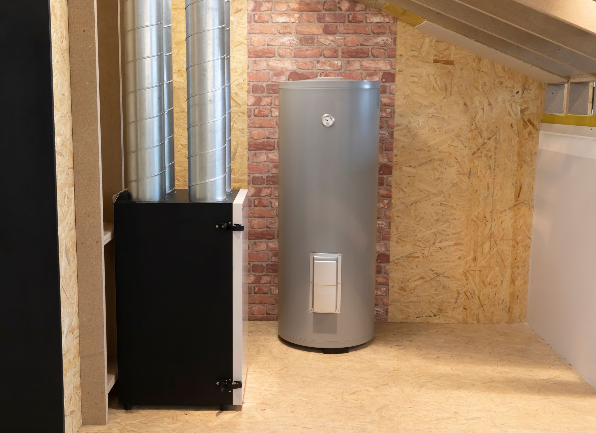 A water heater is sitting in a room next to a brick wall.