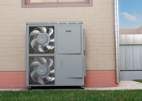 A large fan is sitting on the side of a brick building.