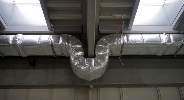 A large duct is hanging from the ceiling of a building.