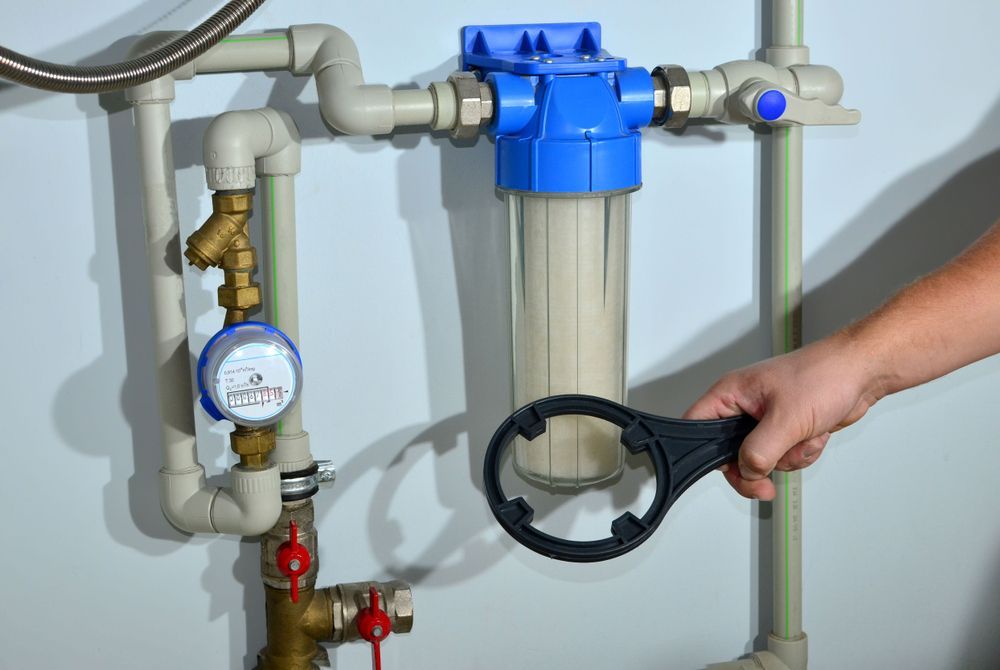 Hand Holding a Wrench, Near a Water Filter System — J & H Plumbing and Gas in Holt, ACT