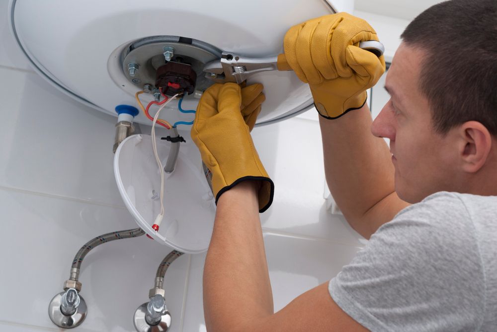 Man in Gloves Working on A Water Heater — J & H Plumbing and Gas in Holt, ACT