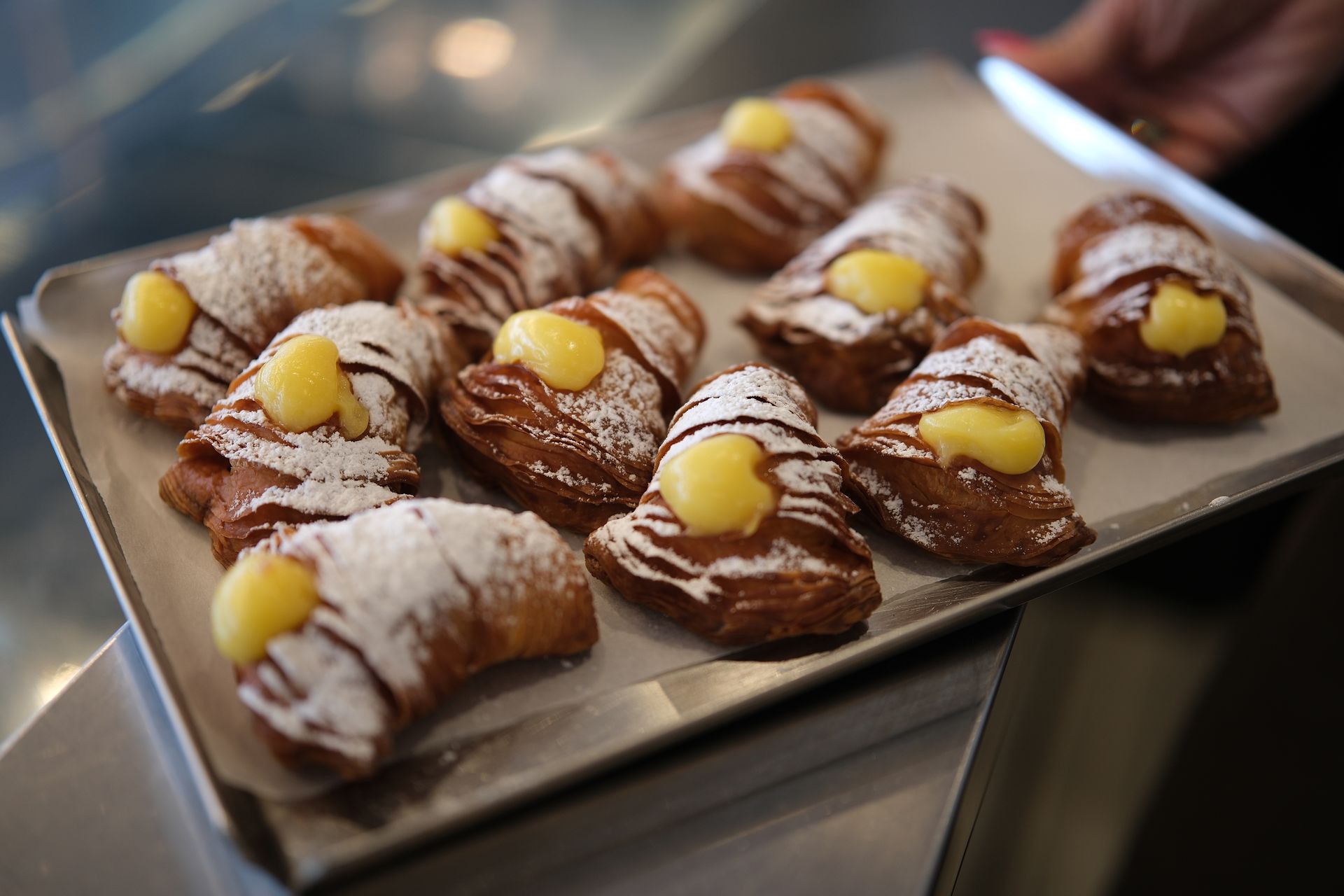 Vassoio di cannoli di pasta sfoglia ripieni di crema e spolverati con zucchero a velo.