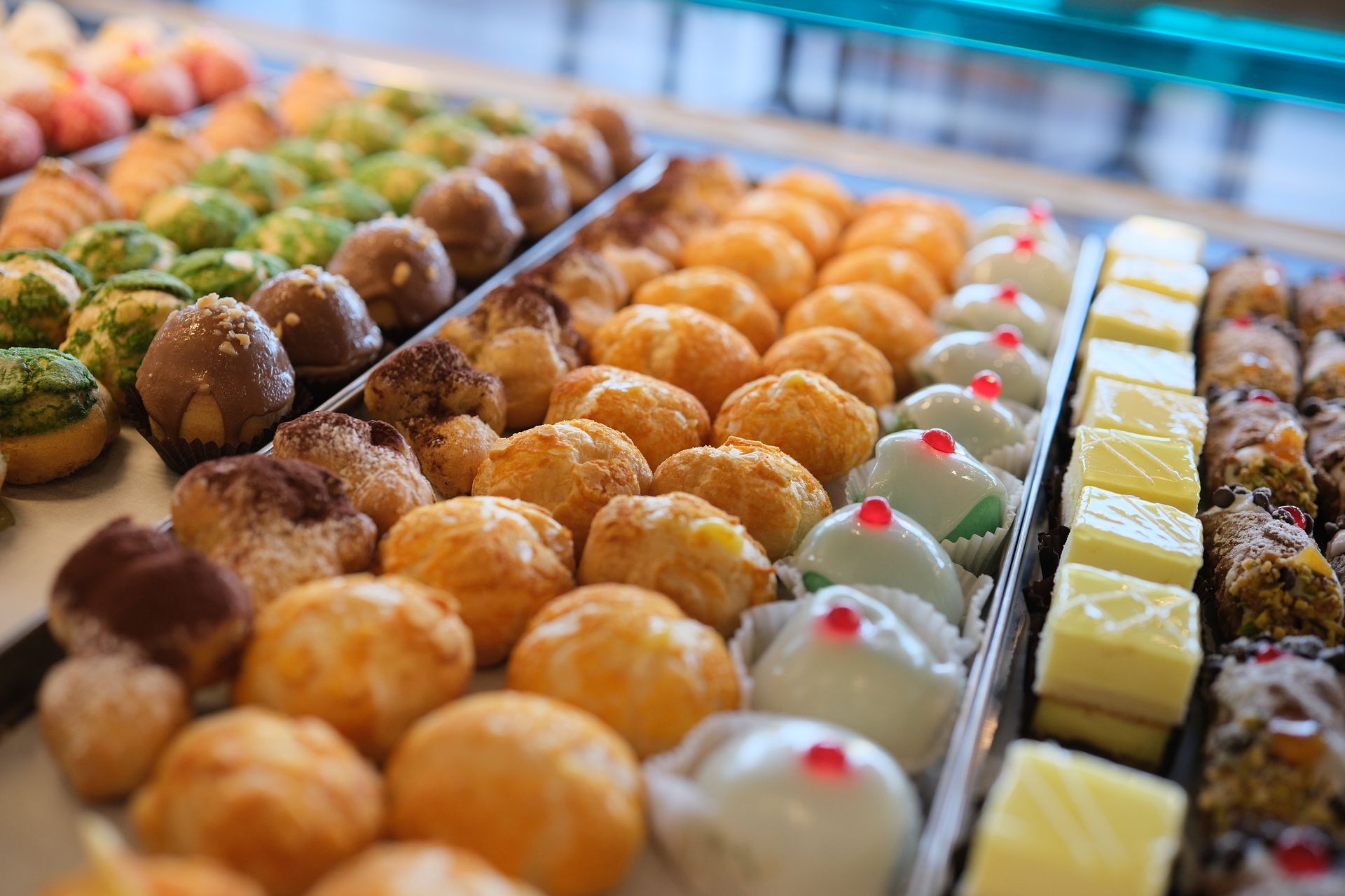 Vetrina con pasticcini assortiti: glassati, spolverati e decorati con vari condimenti.
