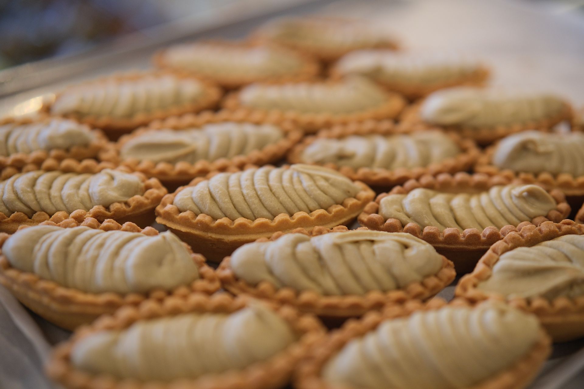 Vassoio di crostatine ovali con bordi arricciati e ripieno a spirale di colore chiaro.