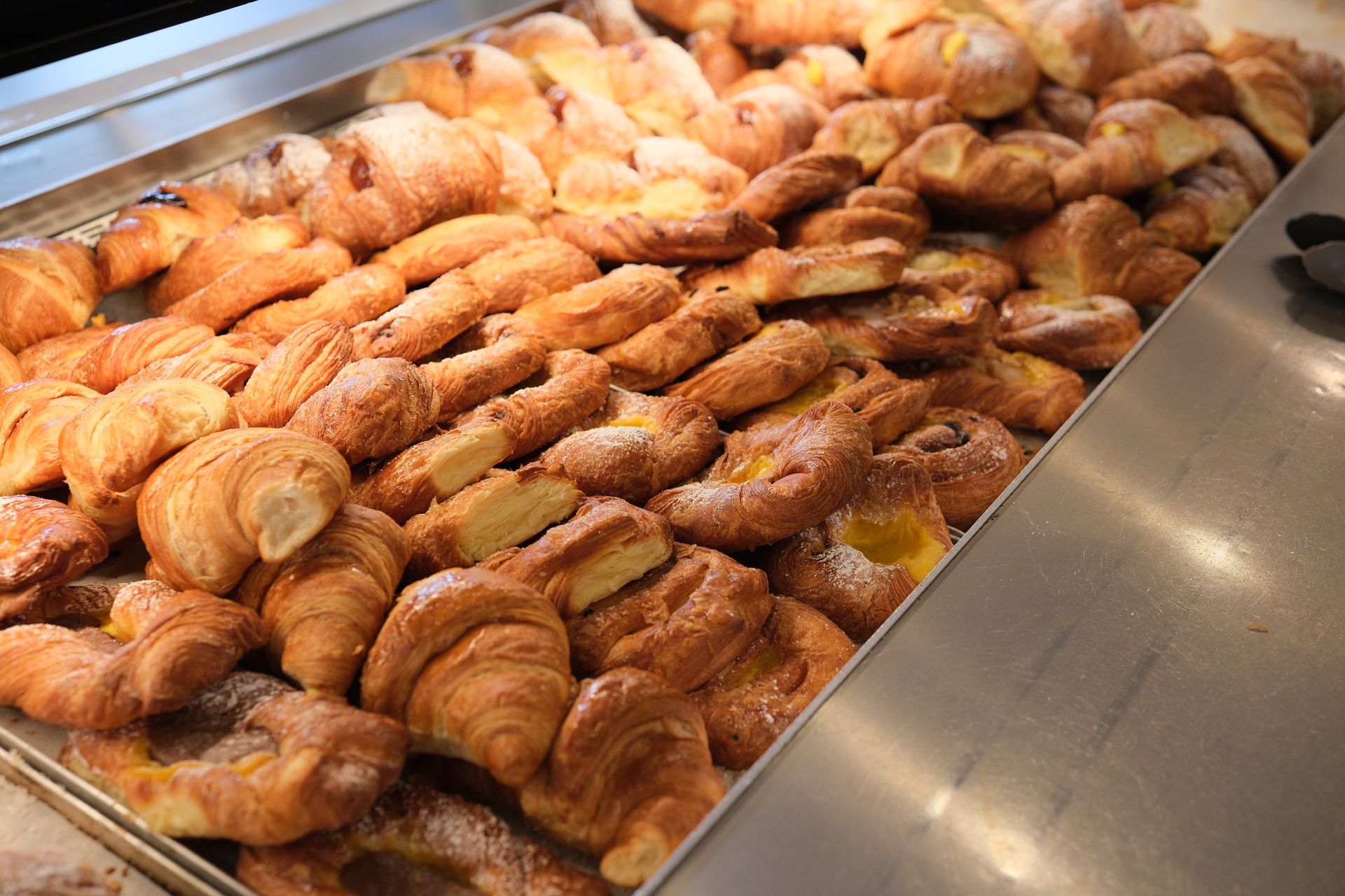 Esposizione di dolciumi, tra cui croissant e danesi, in una vetrina da forno.
