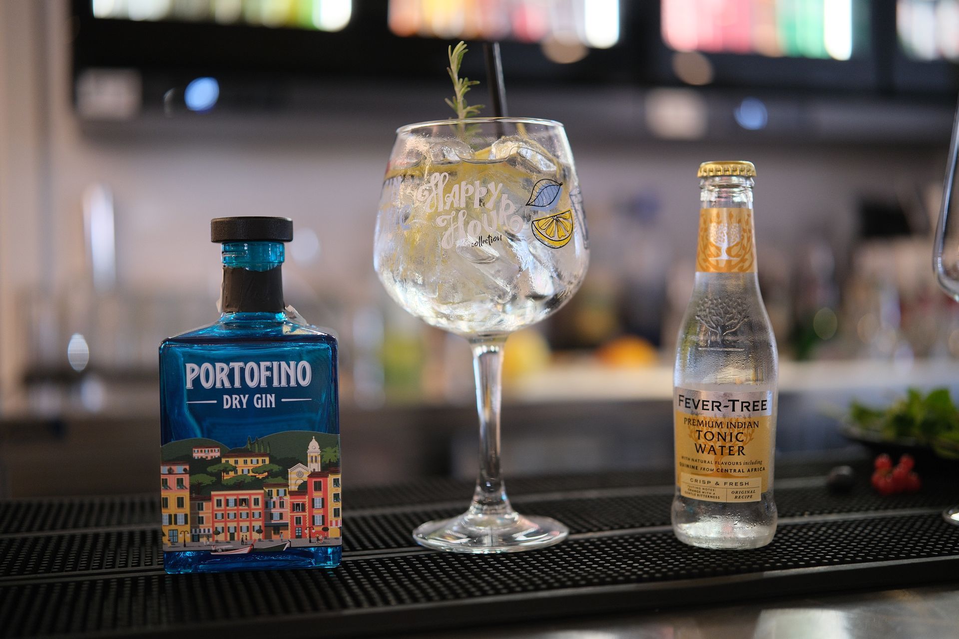 Un cocktail con gin Portofino, acqua tonica e guarnizioni su un bancone bar.