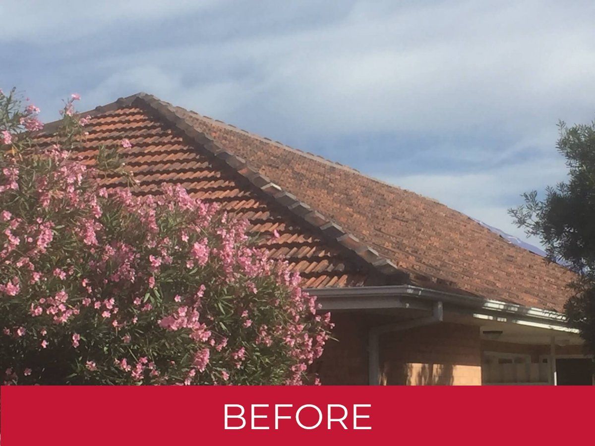 A before picture of a house with a tiled roof and pink flowers.